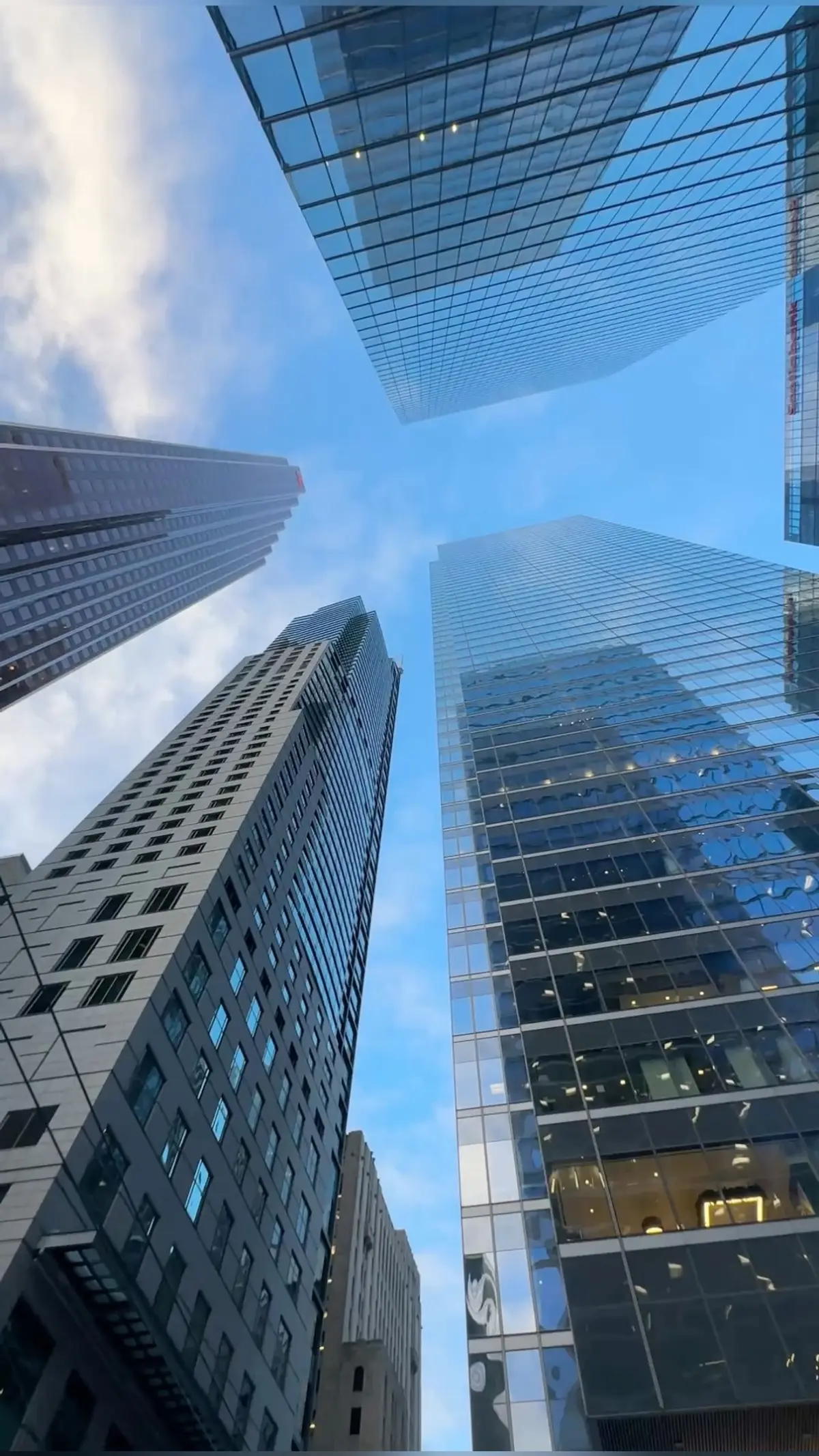 Glass skyscrapers in a financial district viewed from below against a blue sky