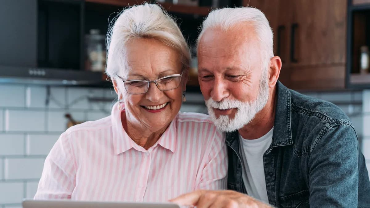 Older couple reviewing documents together on a laptop.